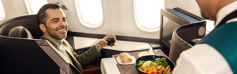A guest in Business being served food by a WestJetter A guest in Business being served food by a WestJetter