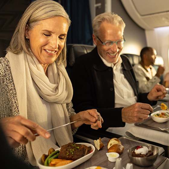 Couple eating a meal together on an airplane Couple eating a meal together on an airplane